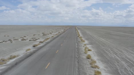 Coche-Conduciendo-Rápido-En-La-Carretera-Abierta-Del-Desierto,-Vuelo-Aéreo-Hacia-Atrás