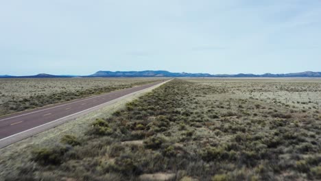 Low-altitude-ascend-drone-reveal-desert-highway-and-single-car-driving