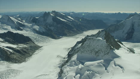 Hochalpiner-Gletscher,-Umgeben-Von-Schneebedeckten-Berggipfeln-Unter-Blauem-Himmel