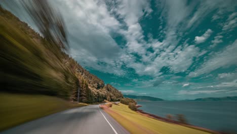 A-speedy-drive-on-the-narrow-two-lane-rural-road-along-the-calm-fjord-near-Sunndalsora,-Norway