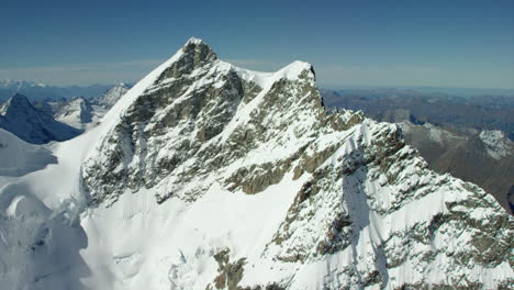 Cima-De-Una-Montaña-Cubierta-De-Nieve-Alpina-Alta-Bajo-Un-Cielo-Azul
