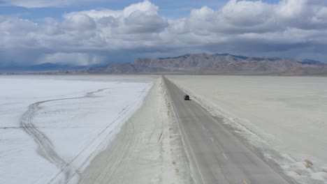 Car-Traveling-on-Long-Straight-and-Narrow-Road-in-Desert,-Aerial-Follow