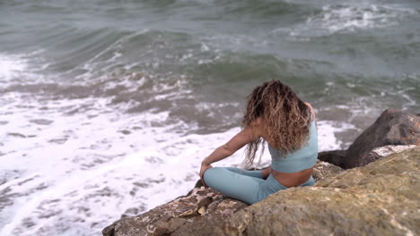 Caucasian-woman-with-curls-stretching-her-body-next-to-the-ocean
