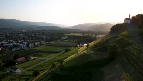 Aerial-drone-video-near-church-on-top-of-a-hill,-close-to-wine-fields,-corn-fields,-apple-orchards-in-Europe