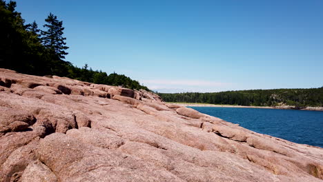 Rocky-shoreline-of-Acadia-National-Park,-view-of-Sand-Beach-in-distance,-static-shot