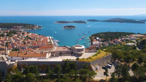 Panorama-of-a-coastal-town-with-many-houses-with-red-roofs,-surrounded-by-the-sea-and-mountains