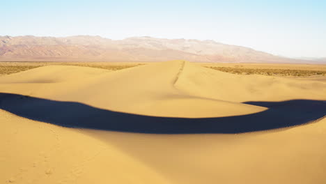 Blick-Von-Links-Nach-Rechts-Auf-Mesquite-Sanddünen-Mit-Fußabdrücken-Im-Death-Valley,-Kalifornien,-USA,-Mit-Bergkette-Im-Hintergrund-An-Einem-Hellen,-Sonnigen-Tag