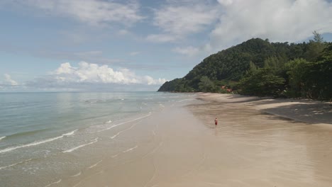 low-angle-aerial-drone-view-man-running-on-tropical-beach-on-Koh-Chang-Island-in-Thailand