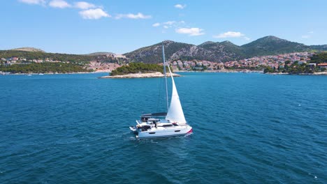 Einsames-Boot-In-Der-Bucht-Nahe-Der-Küstenstadt-Kroatiens-Vor-Dem-Hintergrund-Des-Blauen-Himmels-Und-Des-Blauen-Transparenten-Wassers-Und-Der-Häuser-Mit-Roten-Dächern