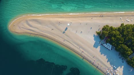 Drone-flight-over-the-coastal-strip,-trees-and-the-beach-in-the-resort-town-of-Croatia-on-the-shores-of-the-Adriatic-Sea-Zoom