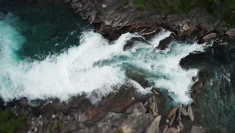 Mesmerizing-sight---a-powerful-flow-of-turquoise-water-rushing-in-the-narrow-and-steep-rocky-riverbed,-foaming,-splashing,-forming-whirlpools-and-eddies-on-its'-way