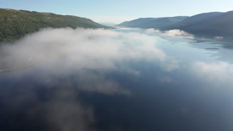 A-morning-flight-above-a-fog,-that-is-slowly-dissipating-over-Nedre-Fiplingvatnet-lake