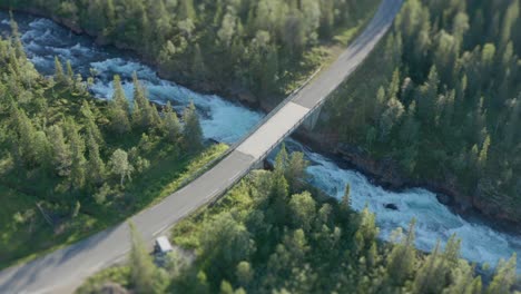 A-two-lane-road-goes-over-a-torrential-flow-in-Storforsen,-Norway