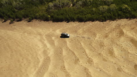 Aerial-tracking-shot-of-vehicles-driving-on-sandy-beach-during-summer-day-in-Queensland,Australia---Adventure-trip-tour-during-sunlight