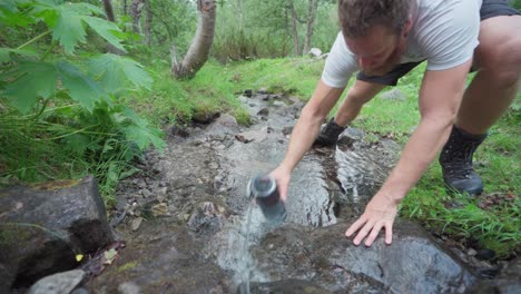 Männlicher-Wanderer-Bekommt-Trinkwasser-Aus-Einem-Sauberen-Gebirgsfluss-In-Norwegen