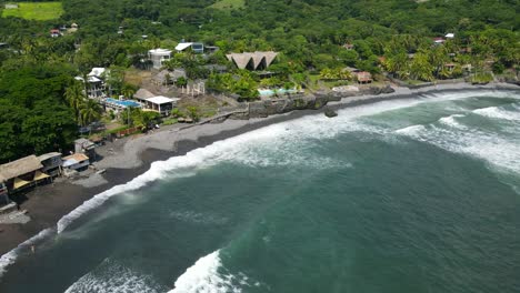 Aerial-view-moving-forward-shot,-scenic-view-of-the-bitcoin-beach-on-a-bright-sunny-day-in-El-Salvador,-Mexico,-hotel-and-coconut-tree-in-the-background