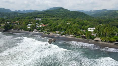 Aerial-view-moving-right-shot,-waves-rushing-to-the-shore-line-of-the-bitcoin-beach-in-El-Salvador,-Mexico,-Scenic-view-of-a-mountain-range-in-the-background