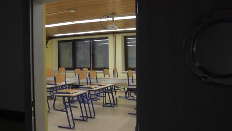 view-of-empty-classroom-through-open-door,-tilt-down-4k