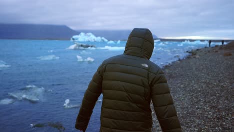 Hombre-Con-Abrigo-De-Invierno-Caminando-Por-La-Laguna-Glacial-De-Jokulsarlon-En-Islandia