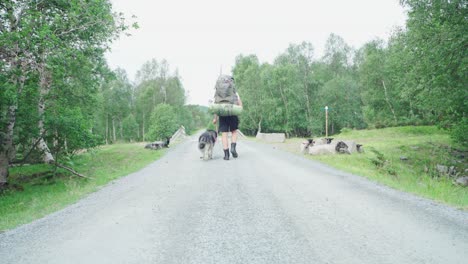 Backpacker-Walking-With-His-Pet-Dog-On-Leash-On-The-Trail-In-Norway