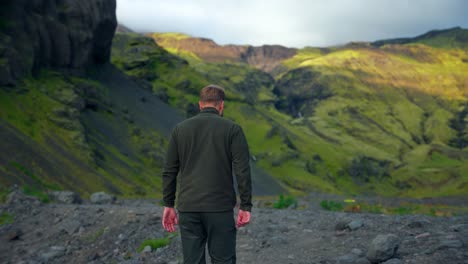 Vista-Trasera-De-Un-Hombre-Caminando-En-Un-Paisaje-Montañoso-Cerca-De-La-Piscina-Al-Aire-Libre-Seljavallalaug-En-El-Sur-De-Islandia