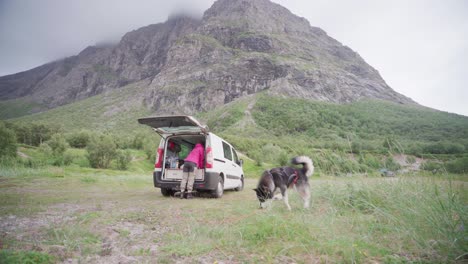 Person-With-Alaskan-Malamute-And-Campervan-Near-The-Mountain-Of-Donnamannen,-Norway