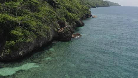 AERIAL---Cliffs-and-jungle-near-Playa-Rincon-beach,-Dominican-Republic,-reverse