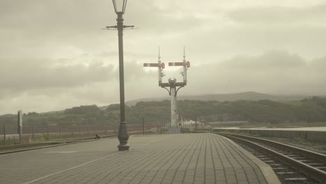 POV-railroad-signals-ahead-as-a-train-rolls-down-the-track,-Snowdonia,-Wales,-UK