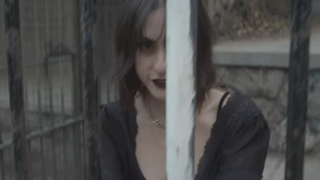 Slow-motion-clip-of-a-gothic-girl-model-smiling-behind-bars-imprisoned-in-a-jail