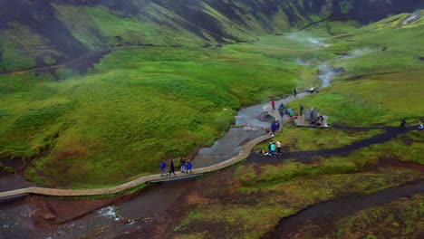 Gente-Caminando-Por-El-Sendero-Junto-Al-Río-Caliente-En-El-Valle-De-Reykjadalur-En-Islandia