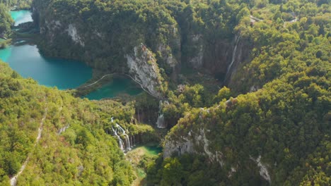 Unglaubliche-Drohnenansicht-Aus-Der-Luft-Auf-Leuchtend-Türkisfarbene-Seen,-Die-Mit-Wasserfällen-Zwischen-Felsigen-Klippen-Und-Dichtem-Wald-Verbunden-Sind