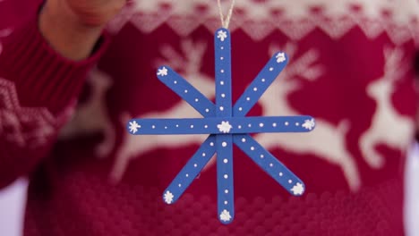 Someone-holding-a-blue-snowflake-made-of-popsicle-sticks