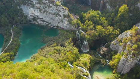 Unglaublicher-Luftblick-Auf-Leuchtend-Türkisfarbene-Seen-Und-Verbunden-Mit-Wasserfällen-Zwischen-Felsigen-Klippen-Und-Dichtem-Wald
