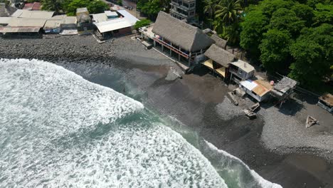 Bird’s-eye-view-full-shot,-a-person-standing-on-the-shore-of-the-bitcoin-beach-on-a-bright-sunny-day-in-El-Salvador-Mexico,-waves-rushing-towards-the-coast