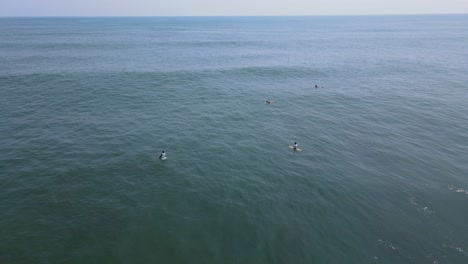 Aerial-view-full-shot,-surfers-waiting-for-the-waves-on-the-bitcoin-beach-in-El-Salvador,-Mexico,-blue-sky-and-sunny-day-in-the-background