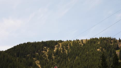 Helicopter-Flying-Over-Mountain-Forest-Lifting-Tree-Log-By-A-Rope