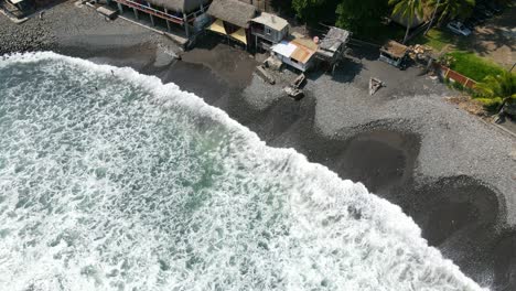 Bird’s-eye-view-full-shot,-people-walking-on-the-shore-of-the-bitcoin-beach-on-a-bright-sunny-day-in-El-Salvador-Mexico,-waves-from-above