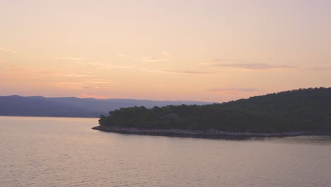 Sunrise,-sunset-over-Adriatic-sea,-behind-a-green,-lush-island