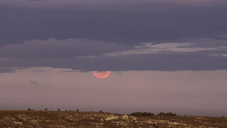 Rise-of-full-glowing-red-moon-with-clouds-above-the-horizon-of-the-earth