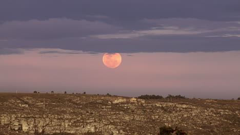 Ascenso-De-Una-Luna-Roja-Brillante-Con-Nubes-Sobre-El-Horizonte-De-La-Tierra