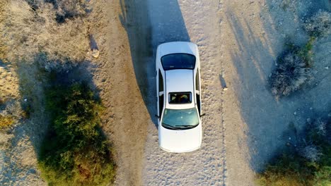 Top-shot-from-drone-of-car-stopping-on-a-gravel-road