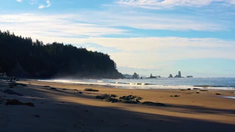 Stunning-rising-and-dollying-in-aerial-drone-shot-of-the-gorgeous-Third-Beach-in-Forks,-Washington-with-large-rock-formations,-cliffs,-small-waves-and-golden-sand-on-a-warm-sunny-summer-morning