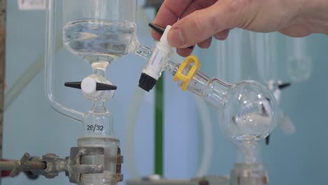 Wissenschaftler,-Der-Das-Ventil-Während-Des-Experimentes-Einstellt,-Flüssigkeit-Im-Glas-Dreht