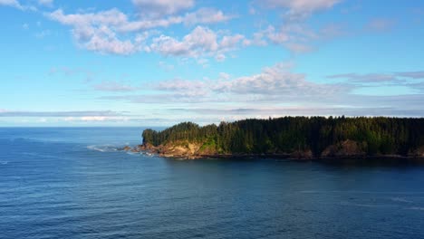 Stunning-rising-aerial-drone-shot-of-the-gorgeous-Third-Beach-in-Forks,-Washington-with-a-forest-or-large-green-pine-trees-on-cliffs-on-a-warm-sunny-summer-morning-with-clouds