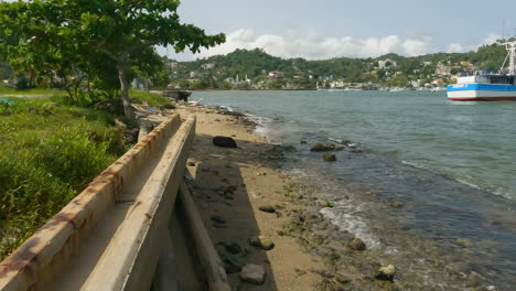 Meereswellen-Am-Felsigen-Ufer-Mit-Festgemachten-Booten-An-Einem-Sonnigen-Tag-In-Samana,-Dominikanische-Republik