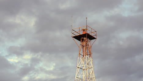 Rotating-beacon-light,-mounted-on-a-tower-at-a-small-airport,-is-shown-in-the-evening,-set-against-a-strong-clouds