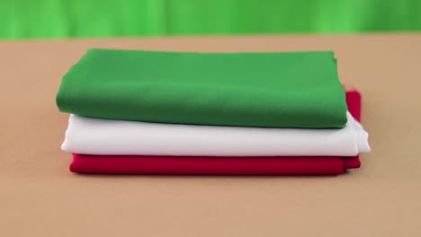 Green,-white-and-red-fabric-panning-on-brown-surface-and-green-background