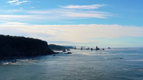 Stunning-aerial-drone-time-lapse-of-the-gorgeous-Third-Beach-in-Forks,-Washington-with-large-rock-formations,-cliffs,-small-waves-and-sea-foam-on-a-warm-sunny-summer-morning