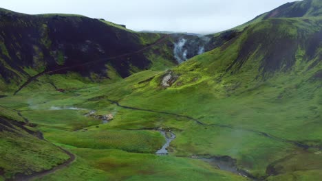 Aerial-View-Of-Tourists-At-Reykjadalur-Valley-With-Green-Mountains-Landscape