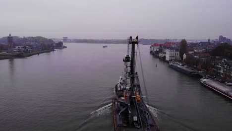 Industrial-Equipment-Loaded-On-A-Freighter-And-Towed-By-A-Tug-Across-The-River-In-Dordrecht,-Netherlands